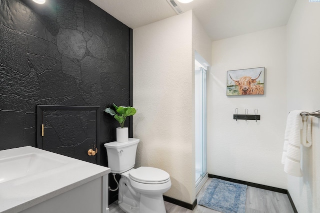 bathroom with wood finished floors, visible vents, toilet, and a stall shower