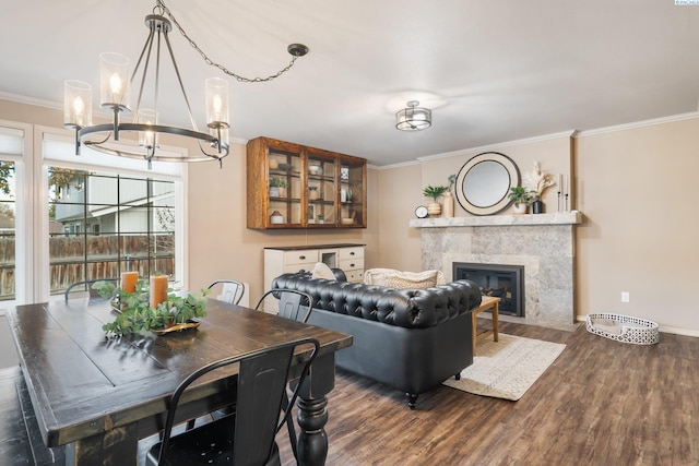 dining area featuring a fireplace, ornamental molding, dark wood-type flooring, baseboards, and a chandelier