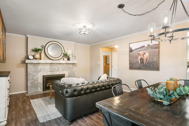 living room featuring dark wood-style flooring, a chandelier, a fireplace, baseboards, and ornamental molding