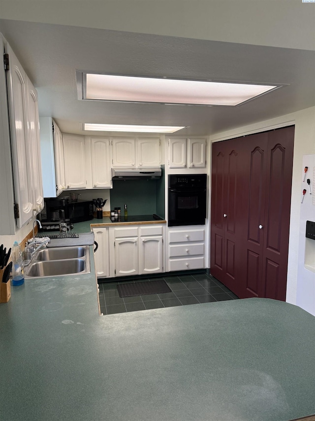 1336 Semillon Pl, Prosser, WA 99350 - kitchen with under cabinet range hood, a sink, dark tile patterned flooring, black appliances, and white cabinetry