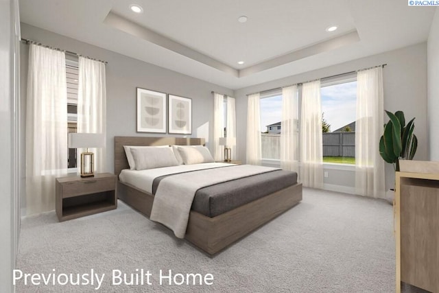 bedroom with a tray ceiling and light carpet