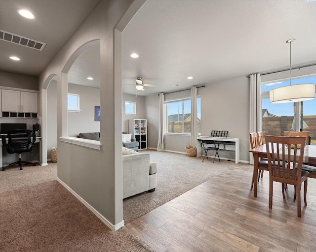 living area featuring arched walkways, recessed lighting, visible vents, wood finished floors, and baseboards