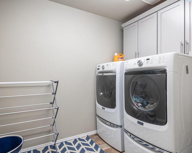 washroom with cabinet space, light wood-style flooring, baseboards, and separate washer and dryer