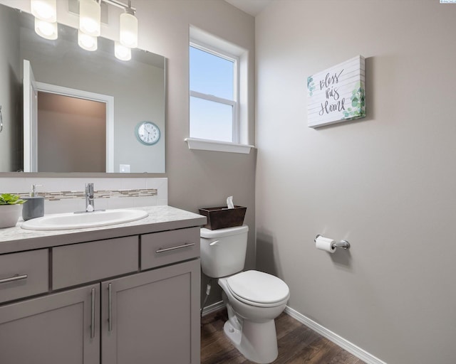 bathroom with vanity, wood finished floors, toilet, and baseboards