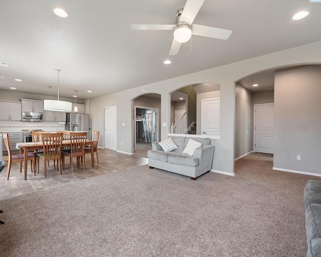 living room with baseboards, arched walkways, carpet flooring, and recessed lighting