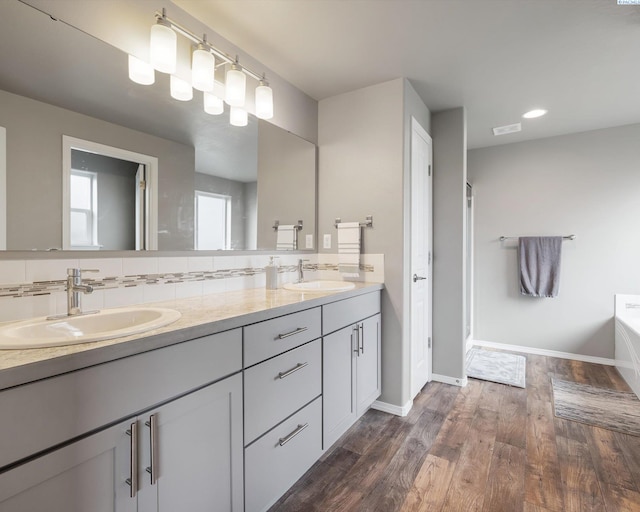 bathroom featuring tasteful backsplash, double vanity, a sink, and wood finished floors