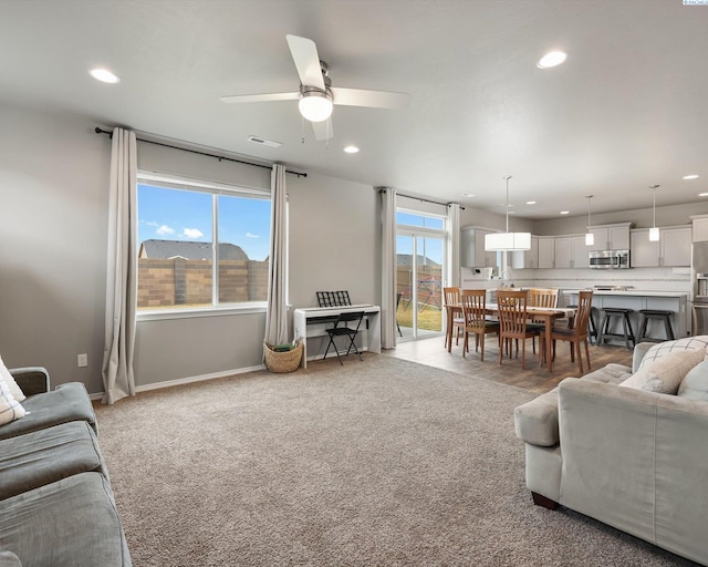 living room featuring baseboards, recessed lighting, visible vents, and light colored carpet