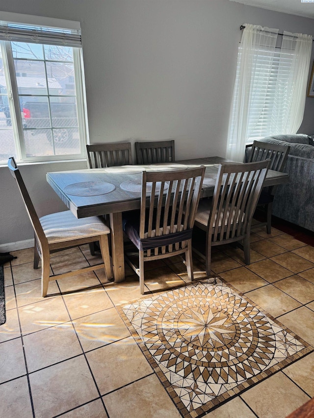 tiled dining room featuring baseboards