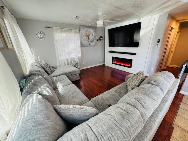 living area featuring a fireplace, wood finished floors, visible vents, and baseboards