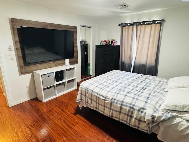 bedroom featuring a closet, wood finished floors, visible vents, and baseboards