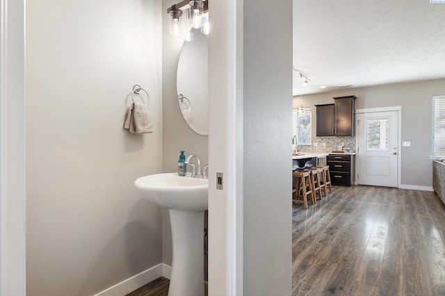 bathroom with a sink, baseboards, decorative backsplash, and wood finished floors