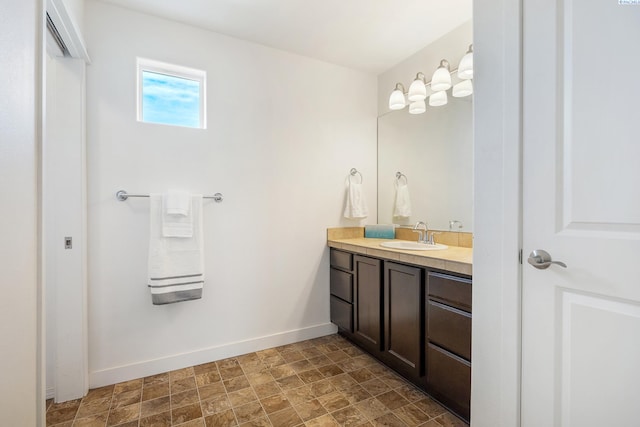 bathroom featuring stone finish flooring, vanity, and baseboards