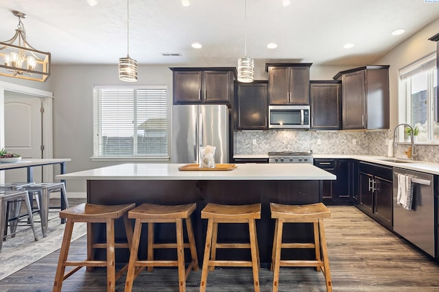 kitchen with appliances with stainless steel finishes, a kitchen island, and pendant lighting