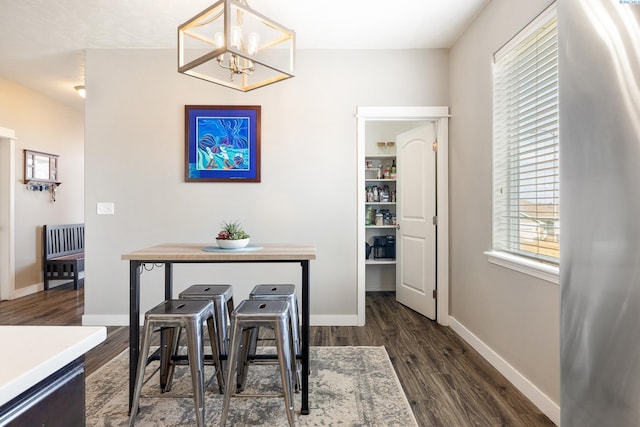 dining room featuring dark wood finished floors, baseboards, and an inviting chandelier