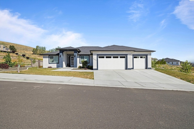 prairie-style house featuring a garage and a front lawn