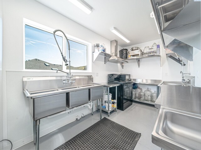 5880 S 58th Ave, West Richland, WA 99353 - kitchen featuring black electric range oven, stainless steel countertops, wall chimney range hood, and concrete flooring