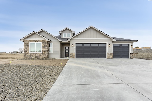 craftsman house featuring a garage, driveway, stone siding, roof with shingles, and board and batten siding