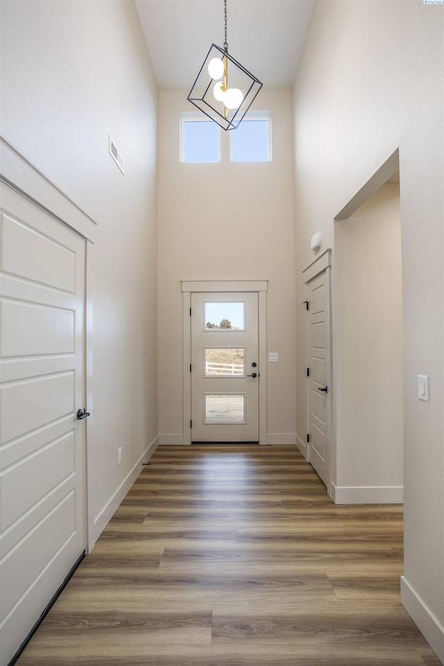 entryway with a towering ceiling, plenty of natural light, baseboards, and wood finished floors