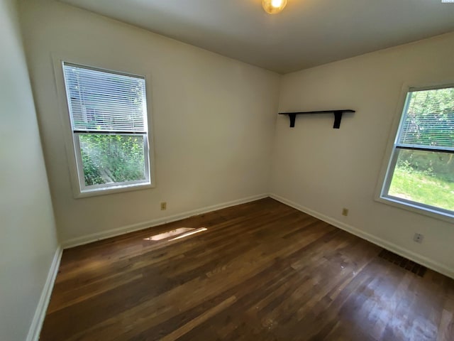 unfurnished room featuring baseboards, visible vents, and dark wood-style floors
