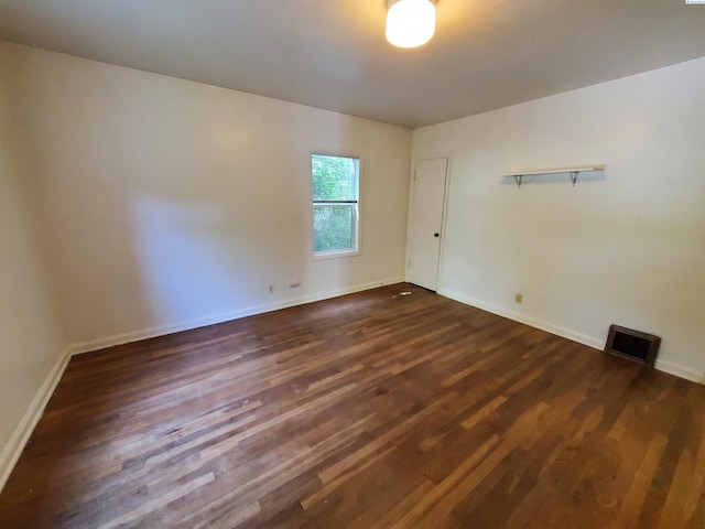 spare room with baseboards, visible vents, and dark wood-type flooring