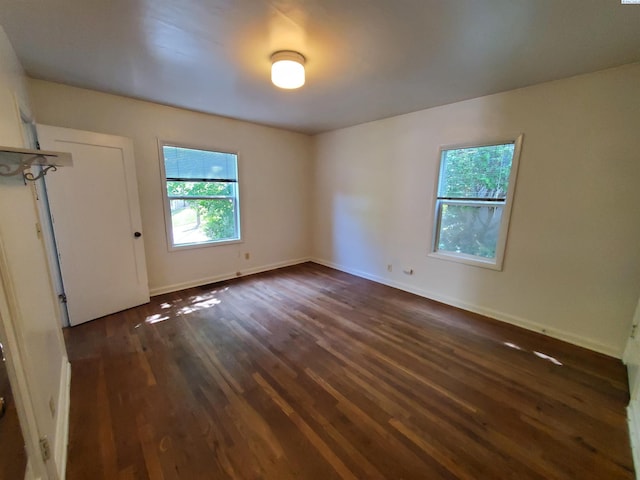 unfurnished room featuring baseboards and dark wood finished floors