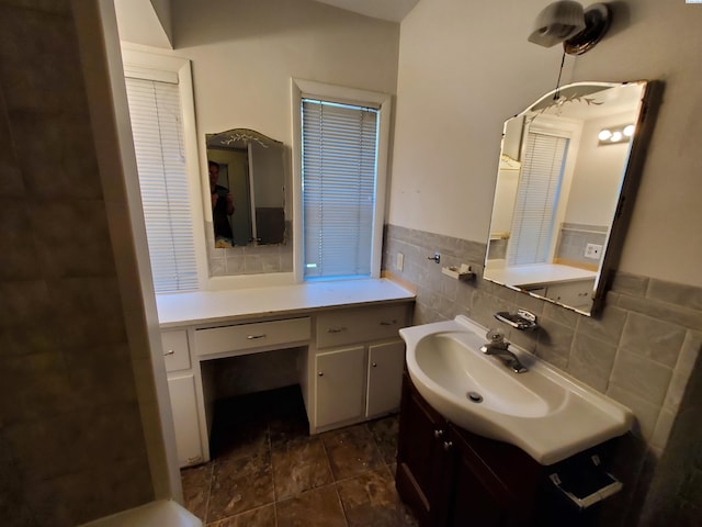 bathroom with vanity, a wainscoted wall, stone finish floor, and tile walls