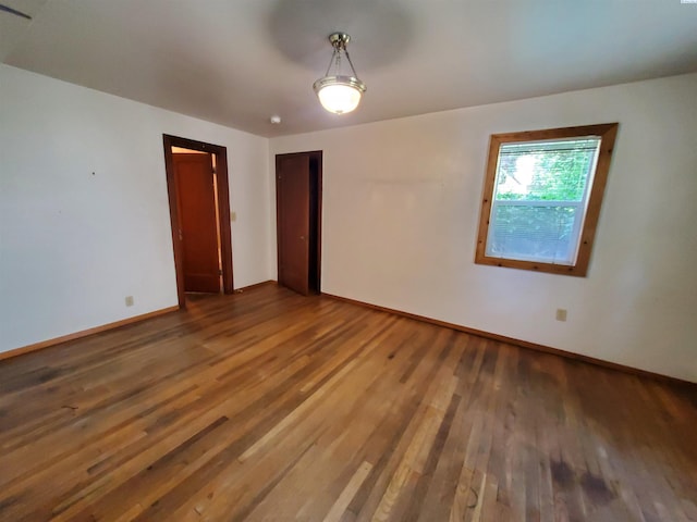 spare room featuring baseboards and wood finished floors