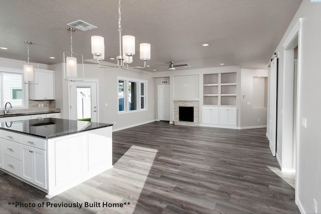 kitchen featuring a kitchen island, pendant lighting, white cabinetry, sink, and a barn door