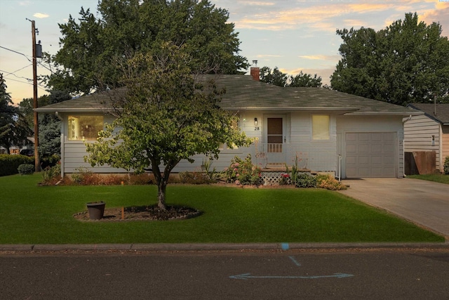 ranch-style house featuring a garage and a lawn