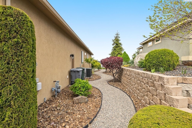 view of side of home with central air condition unit and stucco siding