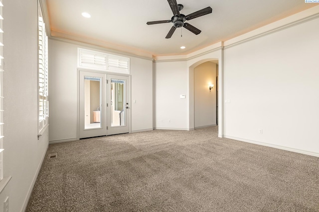 carpeted empty room featuring crown molding, baseboards, ceiling fan, recessed lighting, and arched walkways