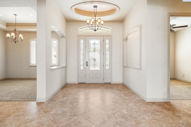 carpeted foyer with a tray ceiling, an inviting chandelier, baseboards, and tile patterned flooring