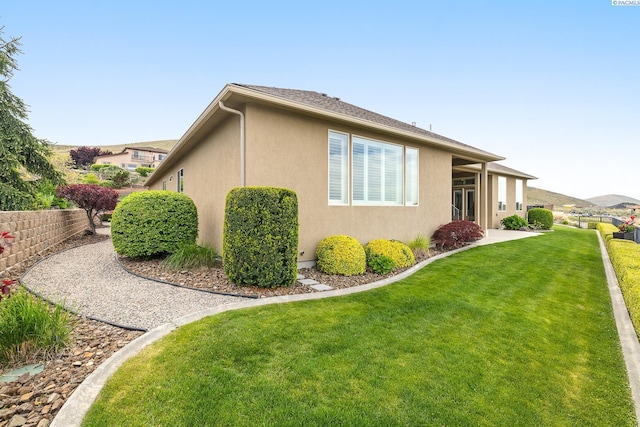 view of home's exterior with stucco siding and a yard