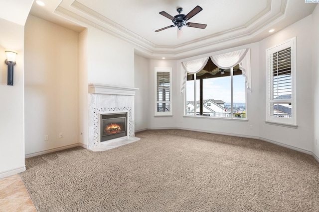 unfurnished living room with crown molding, ceiling fan, a raised ceiling, and a tile fireplace