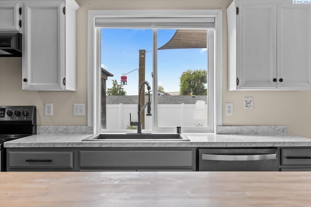 kitchen featuring electric range, dishwasher, a sink, white cabinets, and range hood