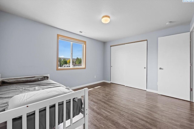 bedroom featuring wood finished floors, baseboards, and a closet