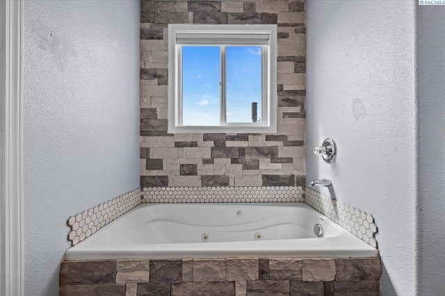 full bath featuring a jetted tub and a textured wall