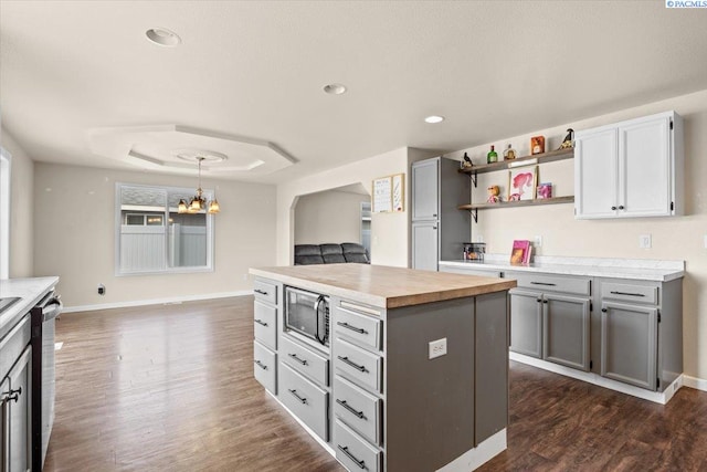 kitchen featuring stainless steel appliances, gray cabinetry, dark wood finished floors, wooden counters, and recessed lighting