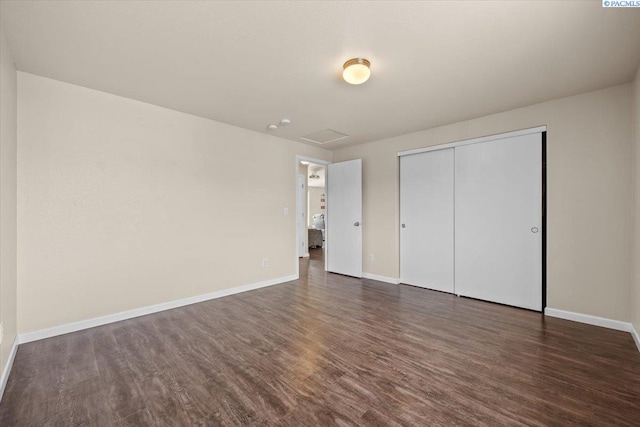 unfurnished bedroom with dark wood-style floors, baseboards, and a closet