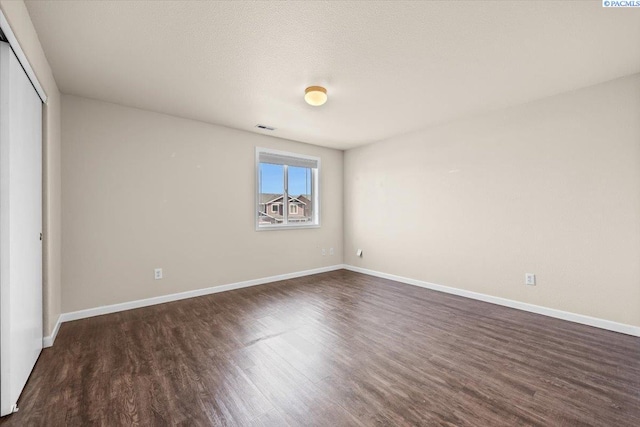 unfurnished bedroom with dark wood-style floors, baseboards, and a closet