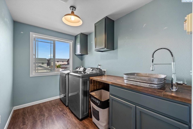 clothes washing area with cabinet space, washer and clothes dryer, dark wood-style flooring, and baseboards