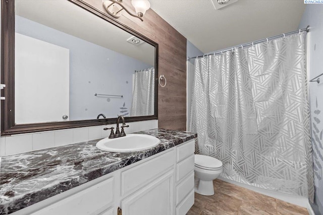 full bathroom featuring toilet, vanity, and wood walls