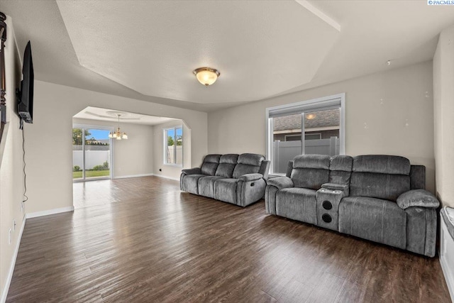 living room featuring a chandelier, wood finished floors, arched walkways, and baseboards