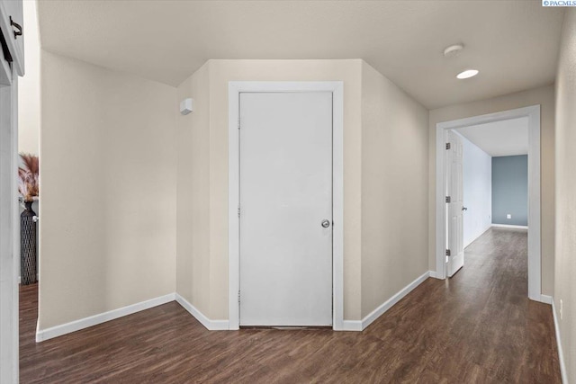 hallway with dark wood-type flooring and baseboards