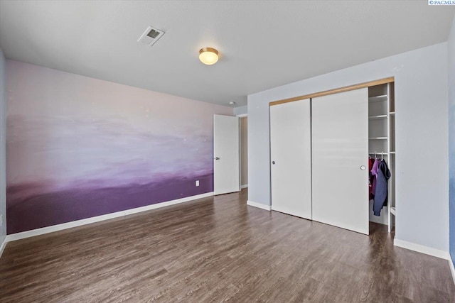 unfurnished bedroom with wood finished floors, a closet, and baseboards
