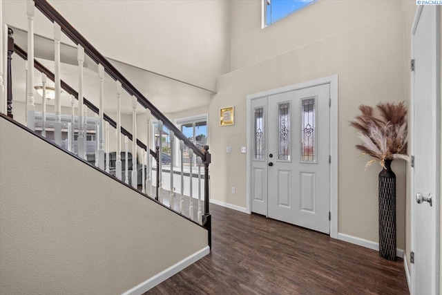 foyer entrance featuring wood finished floors, healthy amount of natural light, baseboards, stairs, and a high ceiling