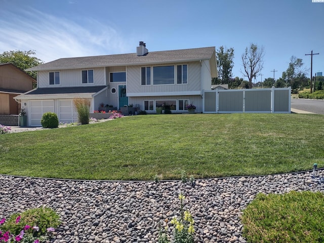 split foyer home with fence, an attached garage, a chimney, a front yard, and driveway