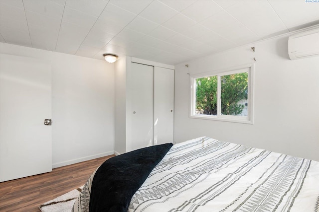 bedroom featuring a closet, dark wood-type flooring, and an AC wall unit