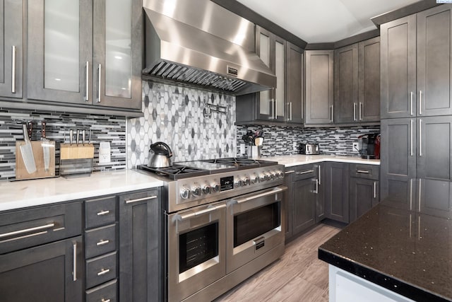9115 W Maple Dr, Pasco, WA 99301 - kitchen featuring double oven range, wall chimney exhaust hood, light wood-style flooring, decorative backsplash, and light stone counters