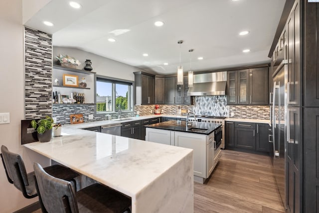 9115 W Maple Dr, Pasco, WA 99301 - kitchen with wall chimney exhaust hood, a peninsula, appliances with stainless steel finishes, decorative backsplash, and recessed lighting